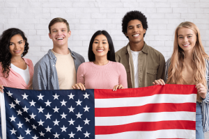 estudiantes de diferentes etnias con la bandera de Estados Unidos
